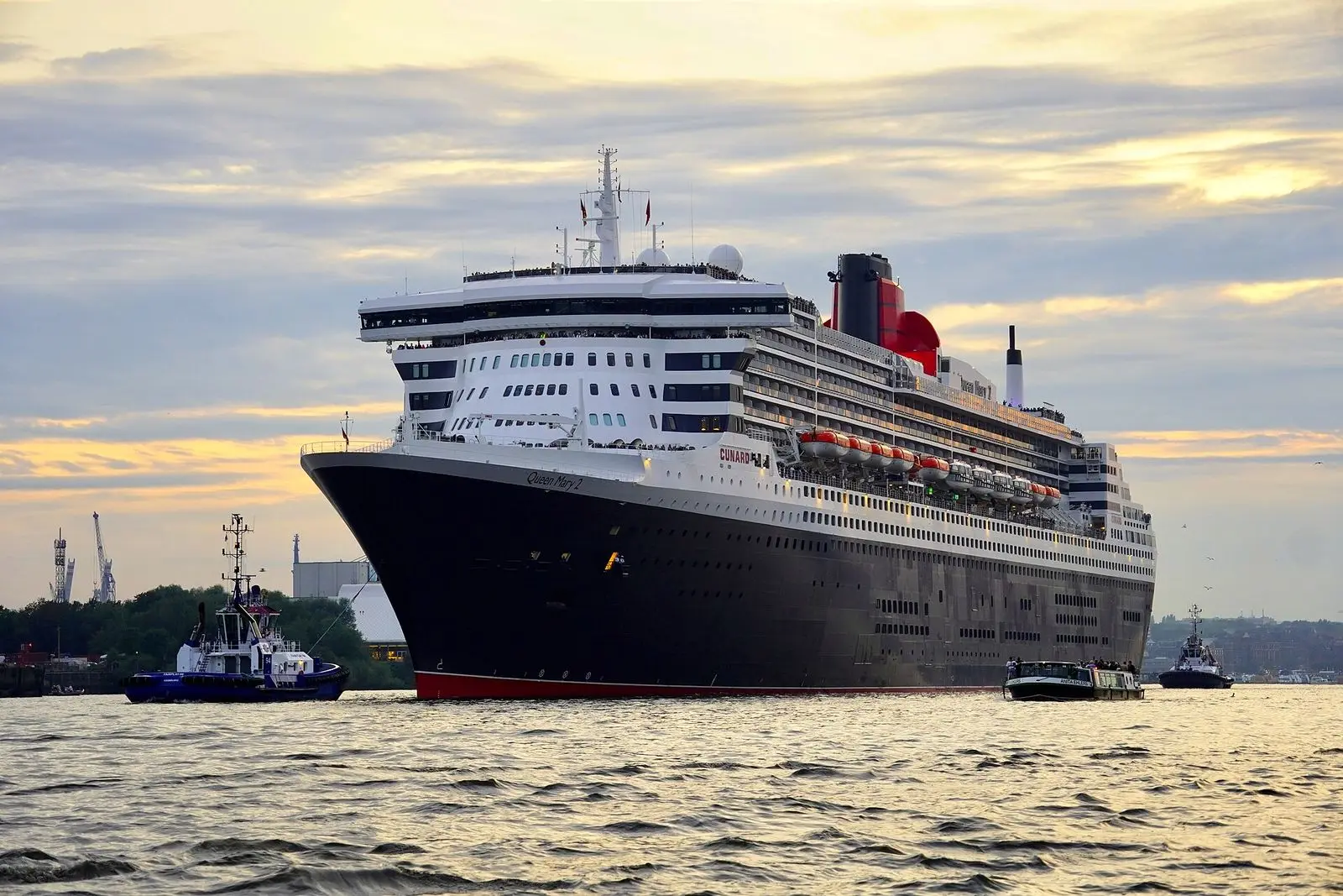 Queen Mary 2 under way in the port of Hamburg, Germany, with tugboats alongside